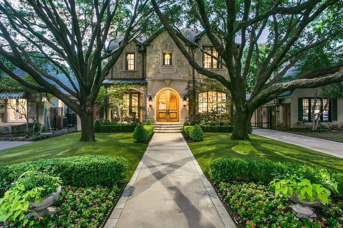 Mature trees framing the walkway to a stone home