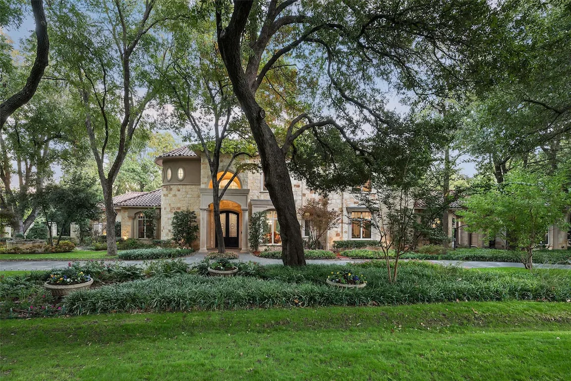 Mature shade trees and landscaped beds beside a home